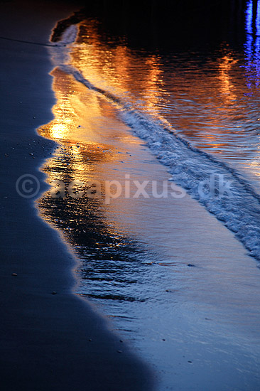 Reflektioner. Lys reflekteres i vådt sand i brændingen på sandstrand; ; Sorrento; Italien; Europa; ; farve, farver, stemninger, stemning, brænding, bølger, romantik, vand