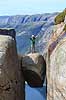 Kjeragbolten. Fjeldvandrer p� Kjeragbolten, en stor sten klemt fast imellem to klippesider 1000 meter (ja) over Lysefjord  Kjerag / Stavanger Norge   Vandring, vandretur, fjeldvandring, turisme, hiking