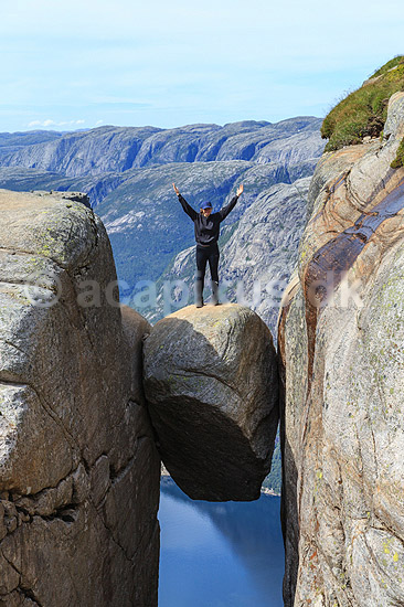 Kjeragbolten. Fjeldvandrer p� Kjeragbolten, en stor sten klemt fast imellem to klippesider 1000 meter (ja) over Lysefjord; ; Kjerag / Stavanger; Norge; ; ; Vandring, vandretur, fjeldvandring, turisme, hiking