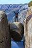 Kjeragbolten. Fjeldvandrer p� Kjeragbolten, en stor sten klemt fast imellem to klippesider 1000 meter (ja) over Lysefjord  Kjerag / Stavanger Norge   Vandring, vandretur, fjeldvandring, turisme, hiking