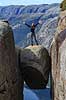 Kjeragbolten. Fjeldvandrer p� Kjeragbolten, en stor sten klemt fast imellem to klippesider 1000 meter (ja) over Lysefjord  Kjerag / Stavanger Norge   Vandring, vandretur, fjeldvandring, turisme, hiking
