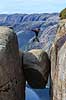 Kjeragbolten. Fjeldvandrer p� Kjeragbolten, en stor sten klemt fast imellem to klippesider 1000 meter (ja) over Lysefjord  Kjerag / Stavanger Norge   Vandring, vandretur, fjeldvandring, turisme, hiking